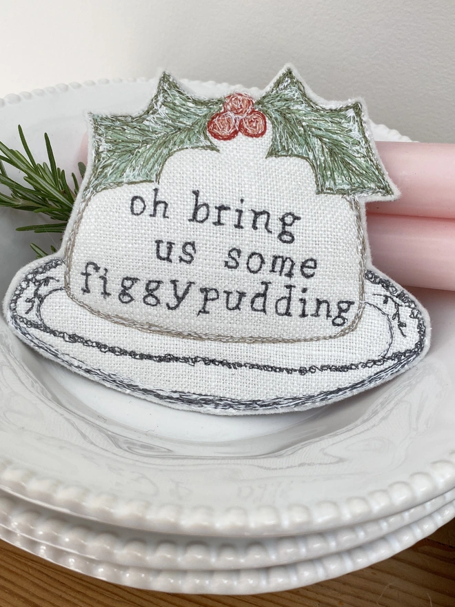 Figgy Pudding Embroidered Fabric Decoration on a plate with candle