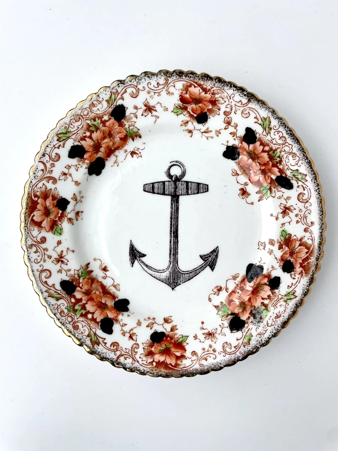 vintage plate with an ornate border, with a printed vintage illustration of an ship's anchor in the middle 