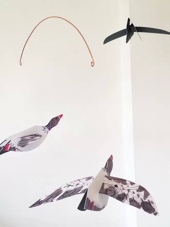 Esther Kent Three Geese illustrated paper mobile, hanging against a white wall.