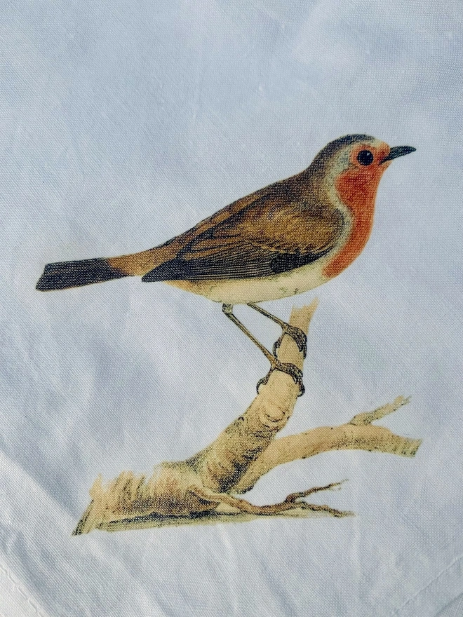 A white cotton napkin printed with a vintage illustration of a robin