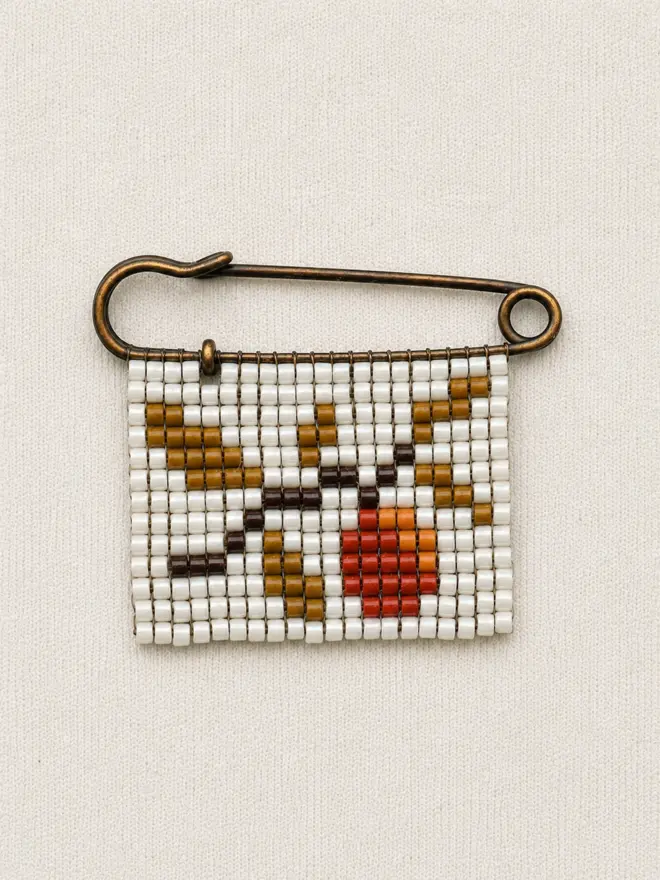 Tiled Beaded Orange Pin. a beaded pin badge with an orange tree branch on a pearl background.