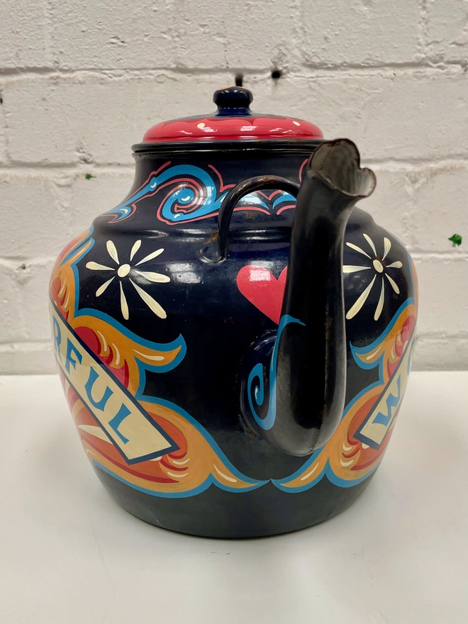 Large dark blue vintage enamel teapot, hand-painted with a oink, orange a yellow fairground inspired design. 'Wonderful' is painted in a banner across the centre of the design.