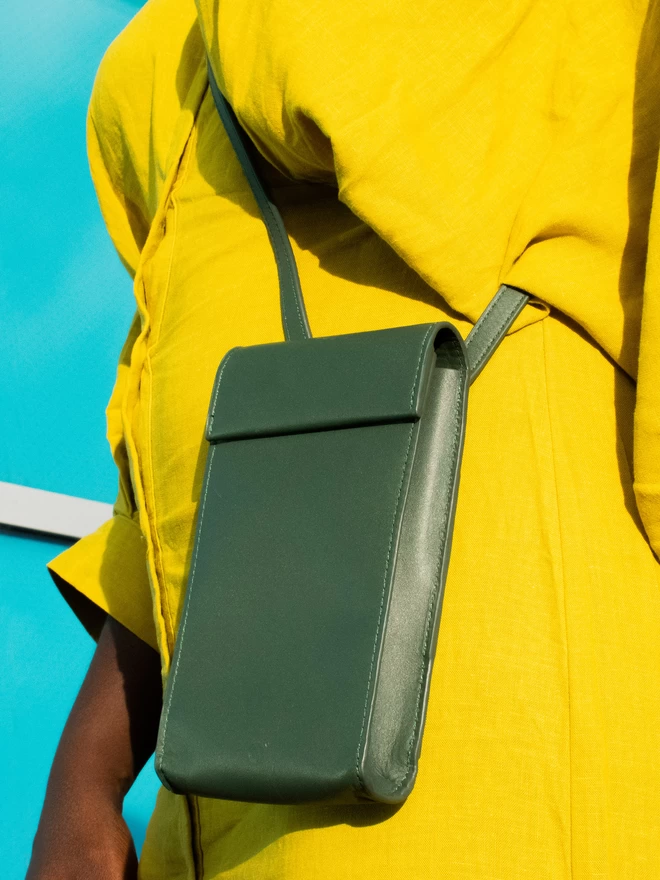 Dark Green Phone Bag worn on a Muted Mustard Dress on a model of darker complexion