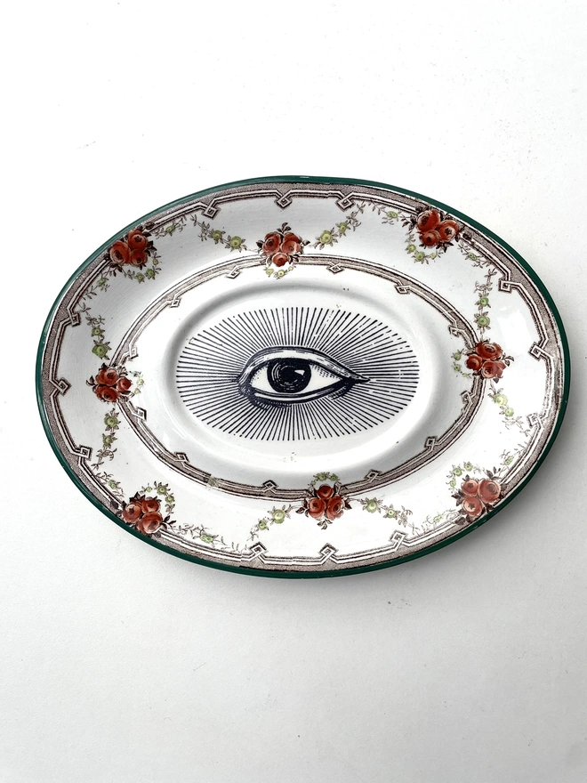 vintage plate with an ornate border, with a printed vintage illustration of an eye in the middle