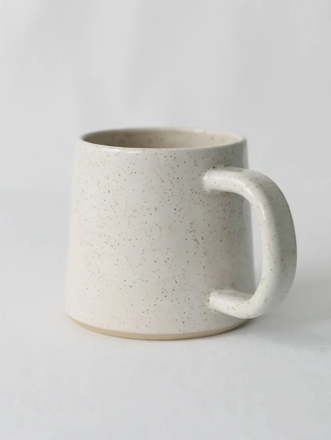 Ceramic Standard Mug, a colourful ceramic mug sitting on a plain surface against a grey backdrop. 