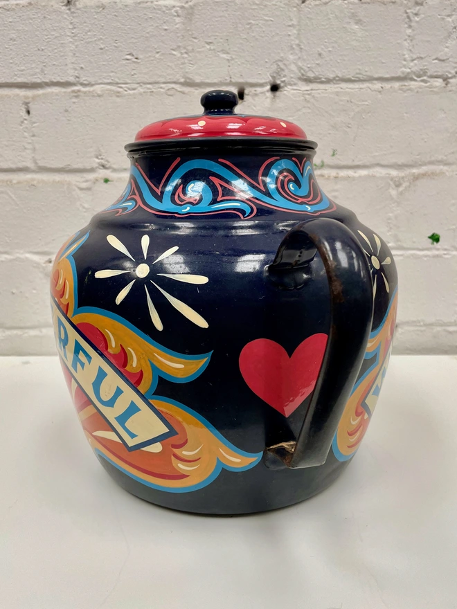 Large dark blue vintage enamel teapot, hand-painted with a oink, orange a yellow fairground inspired design. 'Wonderful' is painted in a banner across the centre of the design.