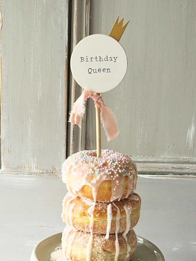 wooden circle shaped cake topper with hand painted message, gold painted crown detail and custom ribbon