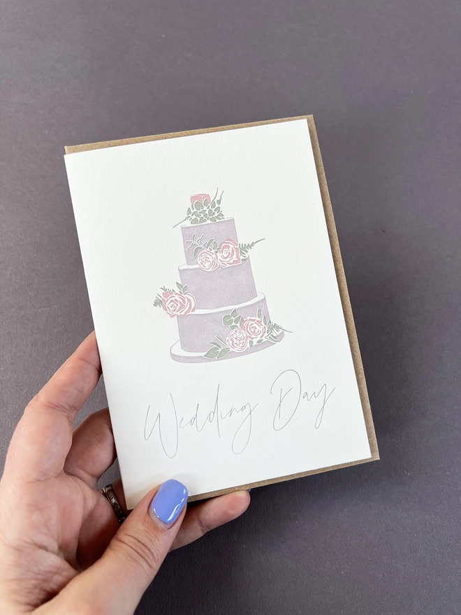 A beautiful floral three tiered pastel wedding cake with "Wedding day" beautifully written in a modern calligraphy underneath.