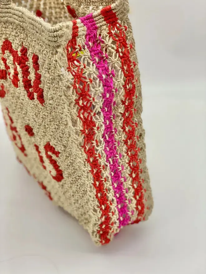 the side of a woven jute bag with red and pink stripes 