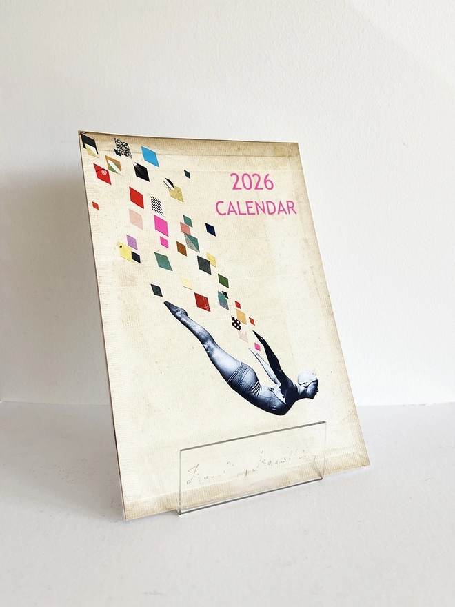 A desk calendar displayed in a clear acrylic stand.
