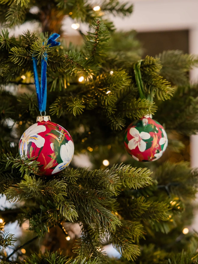 Hand painted floral ceramic christmas bauble dark pink background with Algerian winter iris flowers.