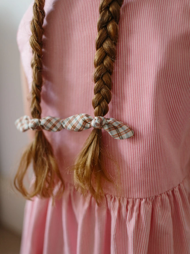 Close up of Little girl with long brown hair wearing rust gingham Hair Bobbles handmade by Runaround Retro