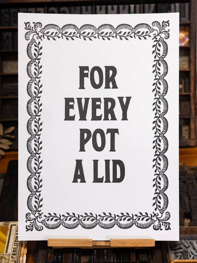 A3 letterpress print with serif block font text design "For Every Pot A Lid" bordered by vintage leaves pattern