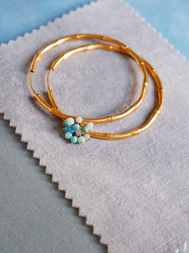 Gold Vermeil Bamboo Hoops with turquoise blue gemstone bead baubles, large, on blue velvet