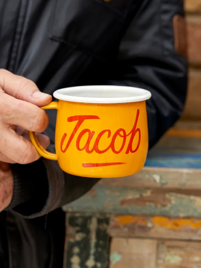 man holding yellow mug with 'jacob' script text