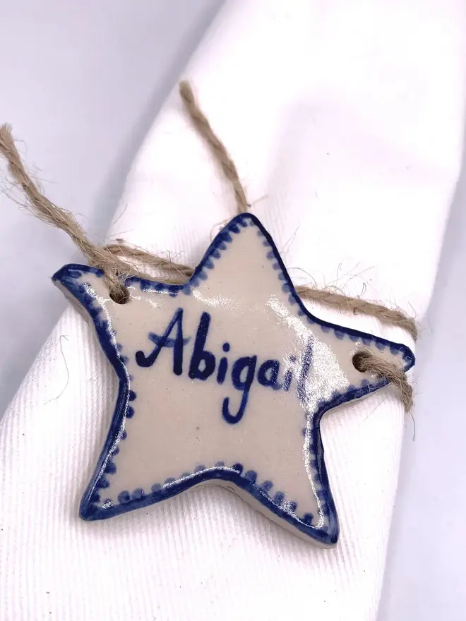 Personalised Ceramic Christmas Star Name Place Markers, a colourful star place marker sitting on a plain white surface. 