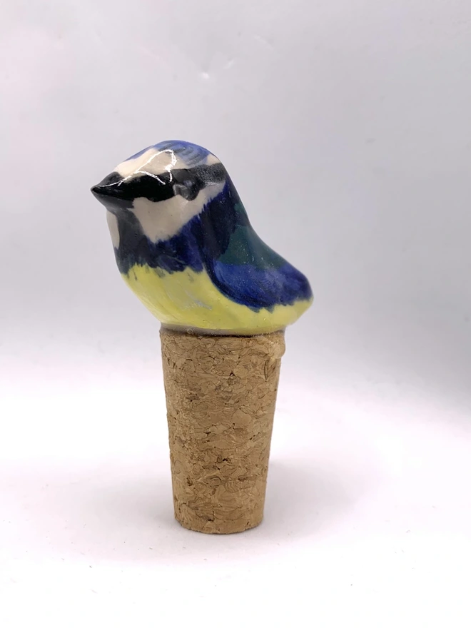 Blue Tit Ceramic Bird Bottle Stop, a bird themed bottle stop sitting on a wine bottle outside