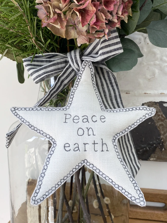 Large Fabric Tree Topper Star on a glass vase with flowers