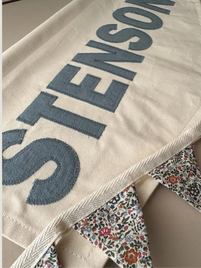 Linen Name Banner.  A large banner with the name STENSON in blue grey linen and floral bunting