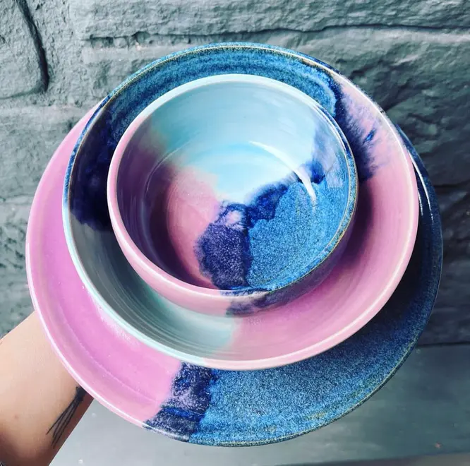 Landscape Dinner Plates (Set Of 4), a stack of dinner plates held by a person in front of a stone backdrop. 