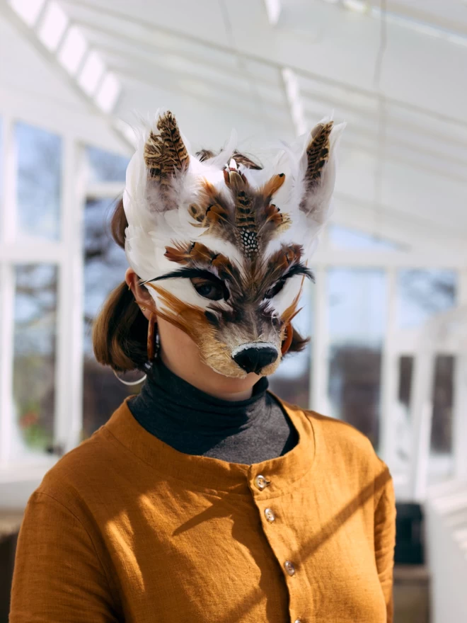 A woman wearing a brown and white luxury wolf party mask down over her face
