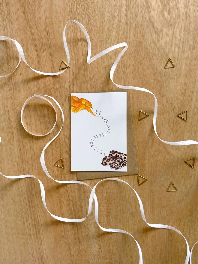 Greetings card with white background featuring two snakes hissing thanks to each other