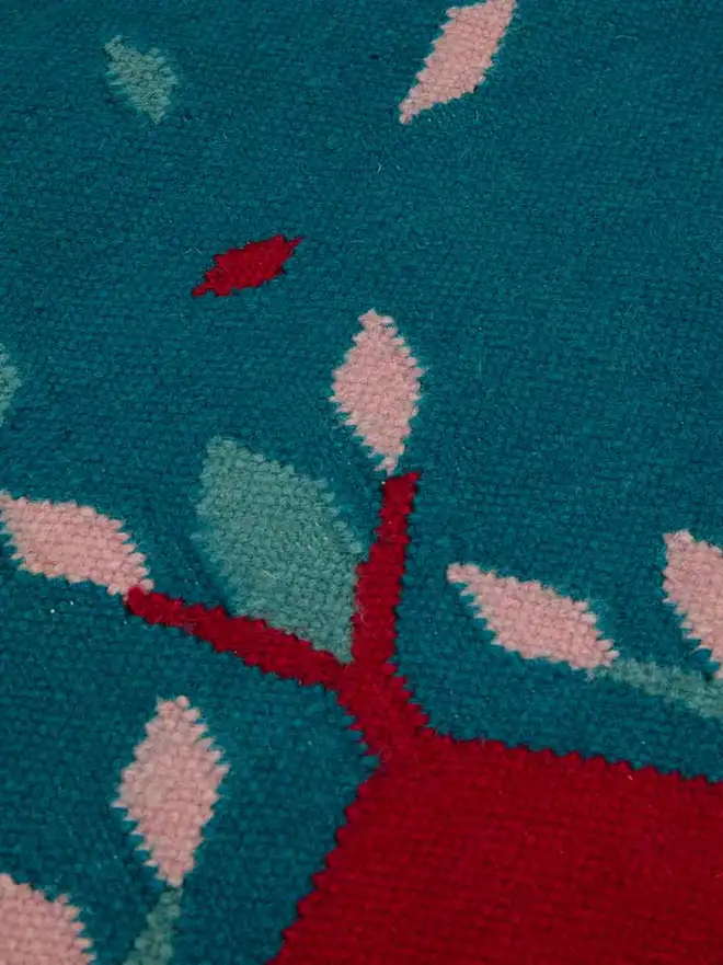 Hedgerow Flatweave Rug, a colourful rug sitting on a plain backdrop. 