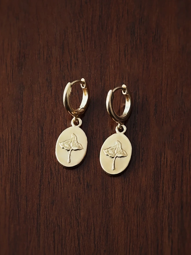 Gold Vermeil Sterling Silver Huggie drop earring with Ivy charms representing friendship and loyalty in the language of flowers on a dark background