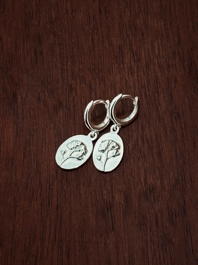 Sterling Silver Huggie drop earring with forget-me-not charms charms on a dark background