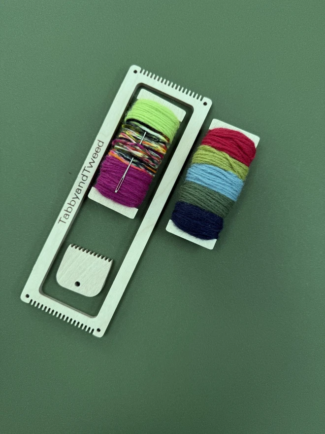 beige rectangular loom with two spools of bright yarn