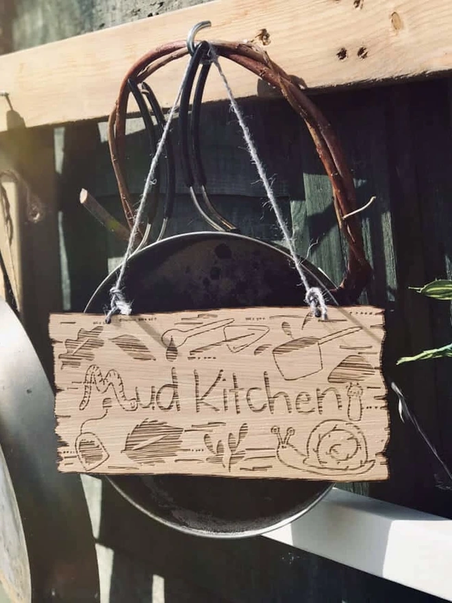 Personalised Wooden Mud Kitchen Sign, a personalised wooden mud kitchen sign hanging from a peg. 