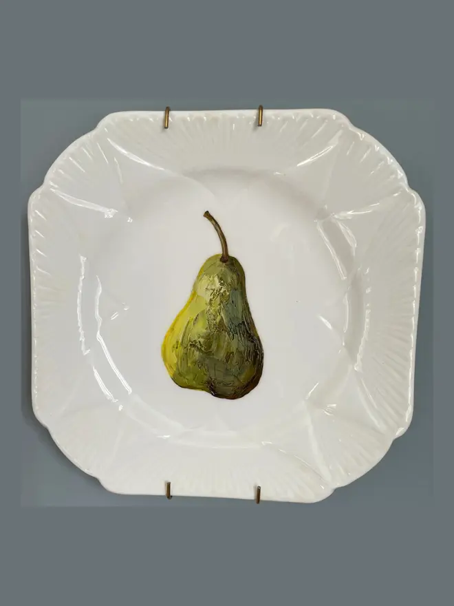 Fine Art Oil Painted Pear On Antique Tea Plate, hanging on a grey background. 