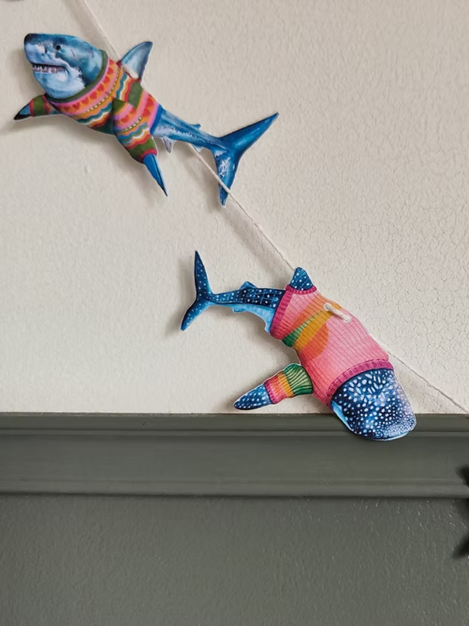 illustrated shark garland. sharks in jumpers on bunting hung up on a wall.