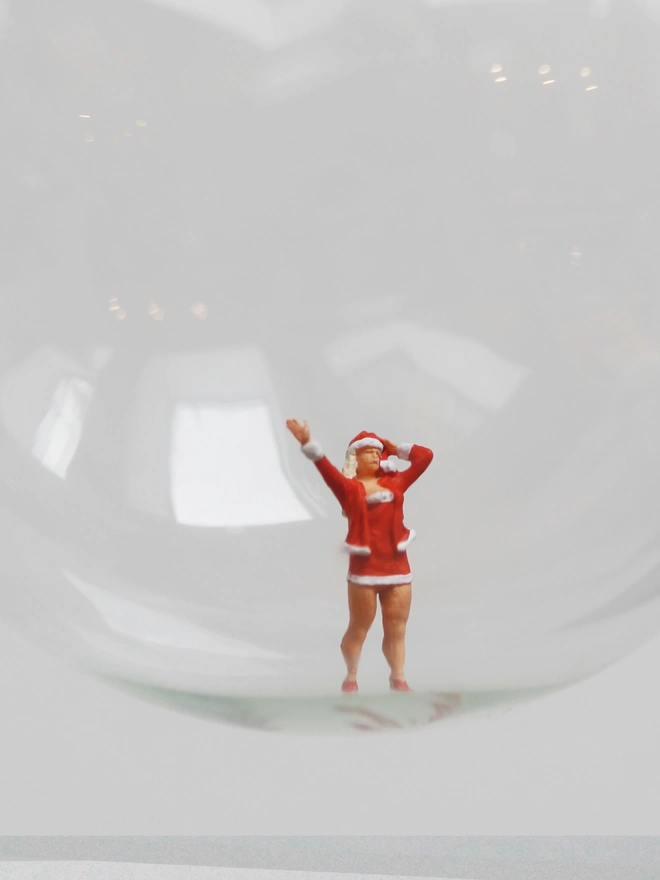 Miniature figure of a female santa in a glass Christmas bauble - close up 