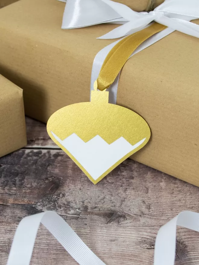 Gold Pendant Bauble Gift Tag shown on present wrapped in brown paper with a white ribbon