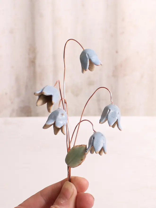 Hand holding bluebell ceramic flower bouquet