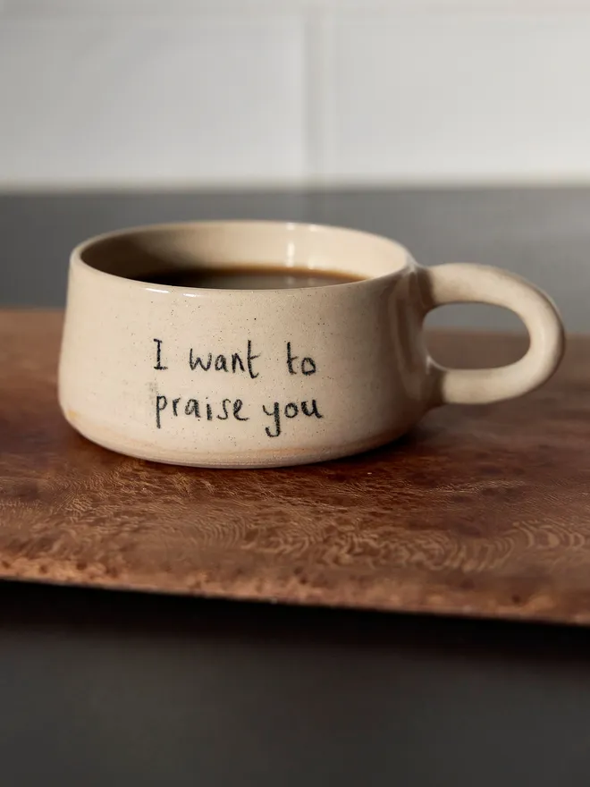 Cream ceramic mug with the words 'I Want To Praise You Mug' written on it 