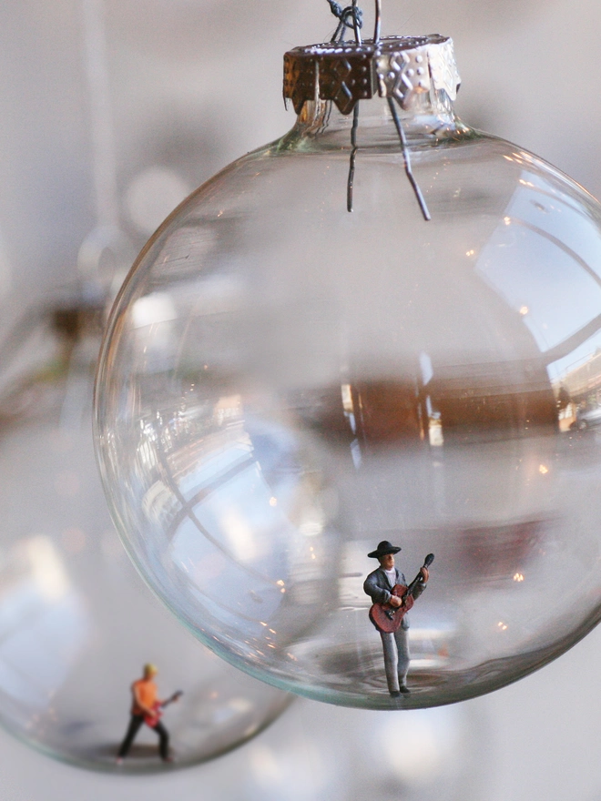 Miniature figure of a acoustic guitarist in a glass Christmas bauble 