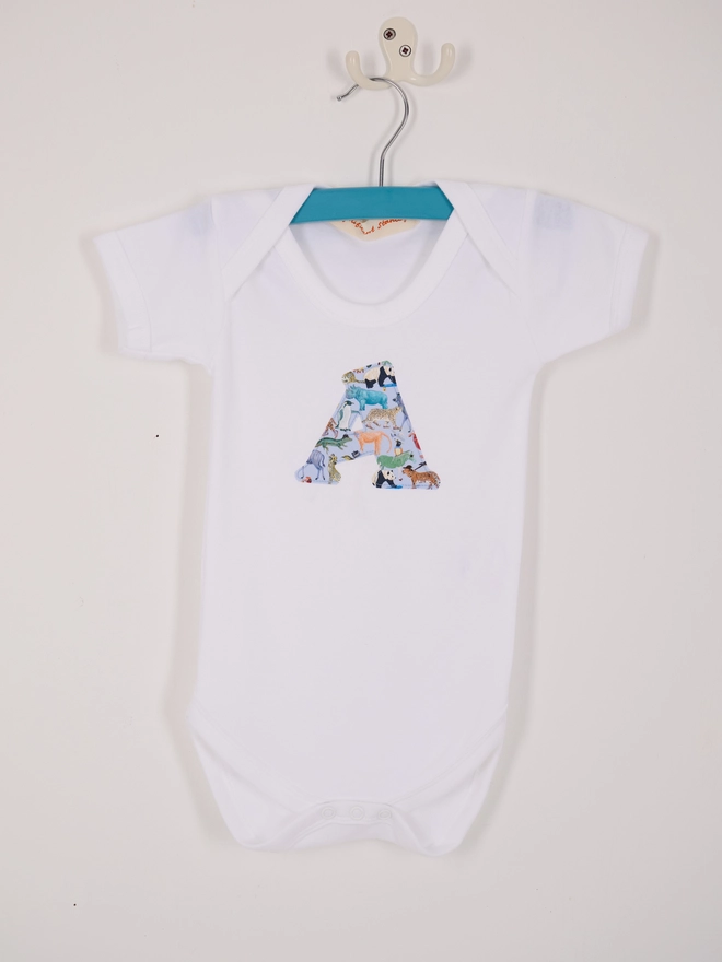 A bodysuit with an initial on the front cut from Liberty zoo animal print