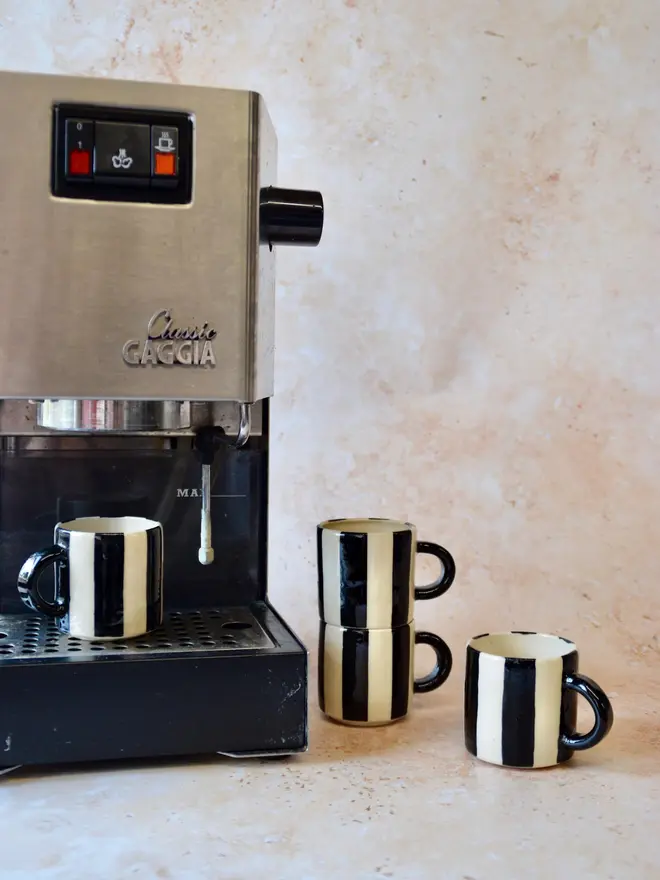 Le Petit Rayé handmade espresso cup beside espresso machine - black and cream stripe