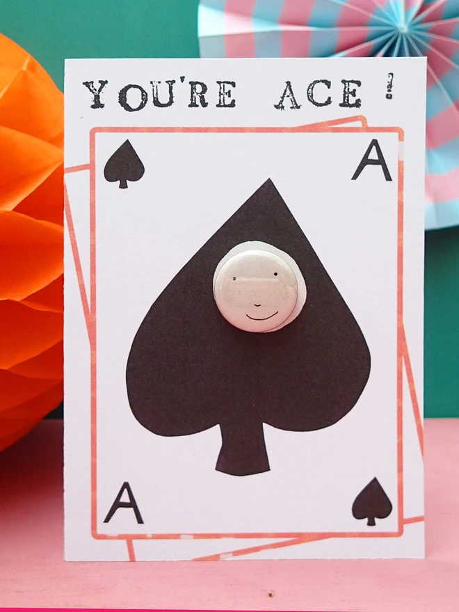 ace of spades greeting card with happy face pin badge