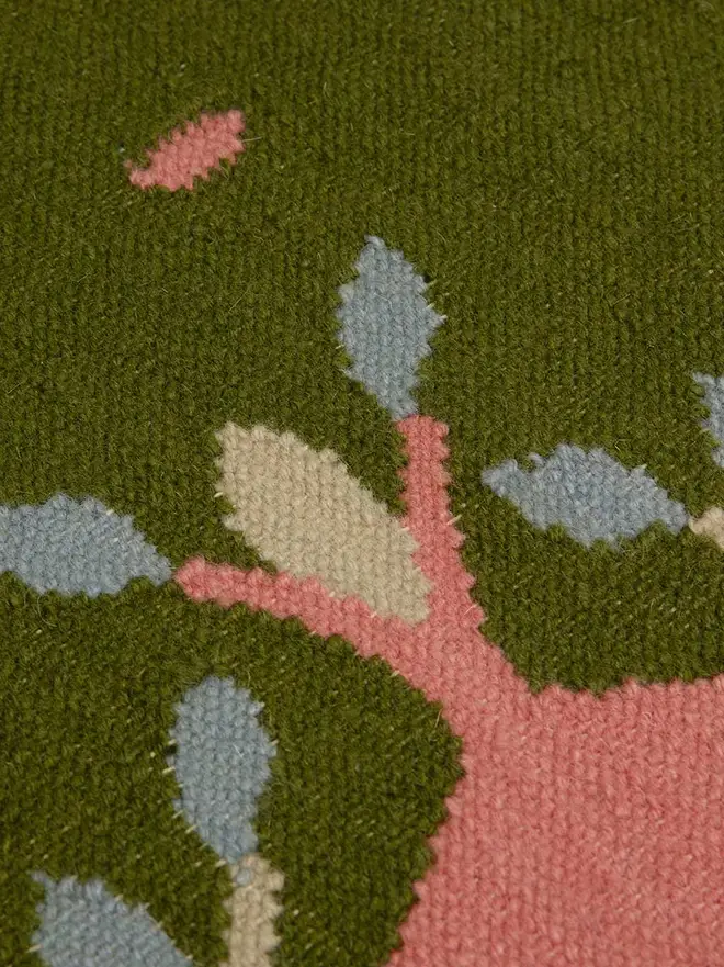 Hedgerow Flatweave Rug, a colourful rug sitting on a plain backdrop. 