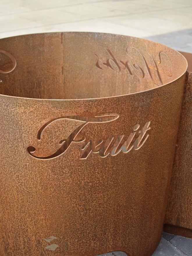 Circle Of Life Corten Vegetable Planter, in room with inscription on it. 