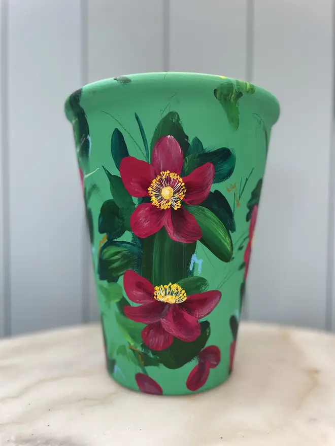 Unique hand-painted terracotta pot featuring deep pink anemone on a turquoise background