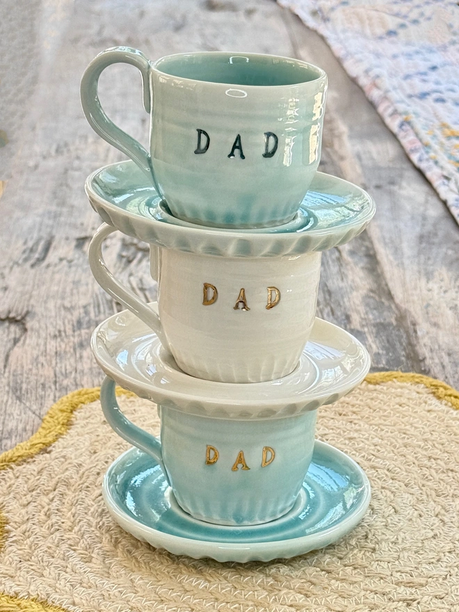 stack of espresso cup and saucers with DAD emblazoned on the side with gold and blue lustre detailing