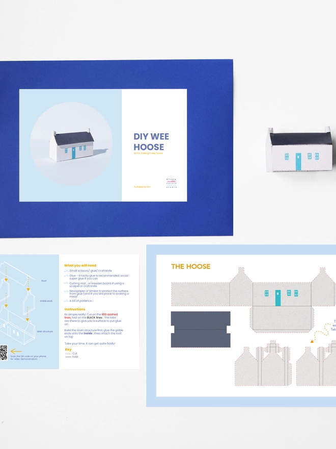 A photo of the elements of the DIY kits laid flat including - instructions, cut out sheet, a bothy made of a paper, an envelope with a label saying it is a DIY kit. 