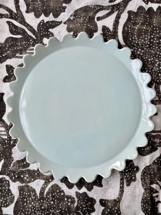 heaven blue dinner plate with daisy scallop edge on patterned cloth