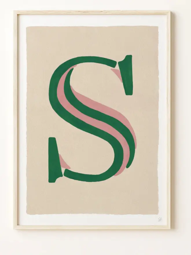 Framed wall art print featuring a large decorative letter “S” in humbug stripes
centered on a white background. 