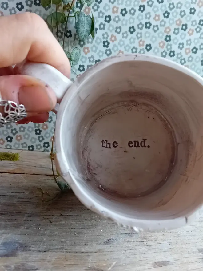 'time for a good read' earthenware mug. a cream mug linocut with 'the end' on the inside base.