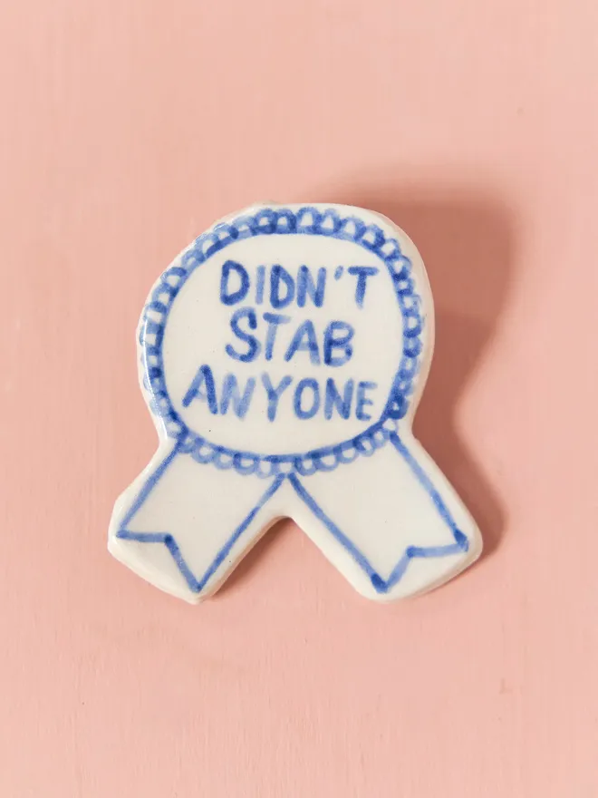  Blue Handmade Ceramic Award , a blue and white ceramic award badge sitting on a pink surface